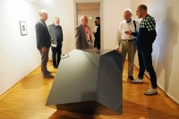 Ralf Brög erläutert Vernissagegästen eines seiner Objekte, dessen Form bereits in einer Radierung Dürers mit dem Titel "Melancholie" aufgetaucht ist.