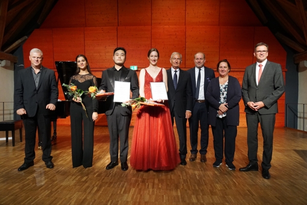 Laura Braun, Runzhe Li und die sie begleitende Pianistin Mar Compte werden flankiert von Bruno Seitz, Dr. Hansjörg Rieger, Moritz von Woellwarth, Theresa Schopper und Dr. Joachim Bläse. 